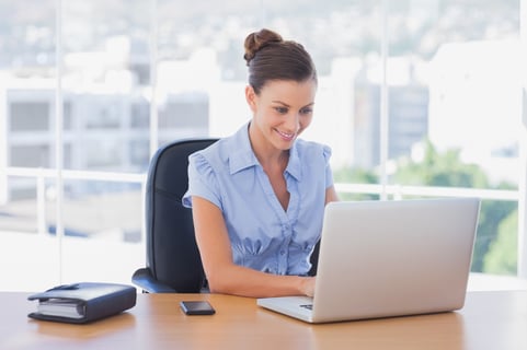 Happy businesswoman working on her laptop in the office