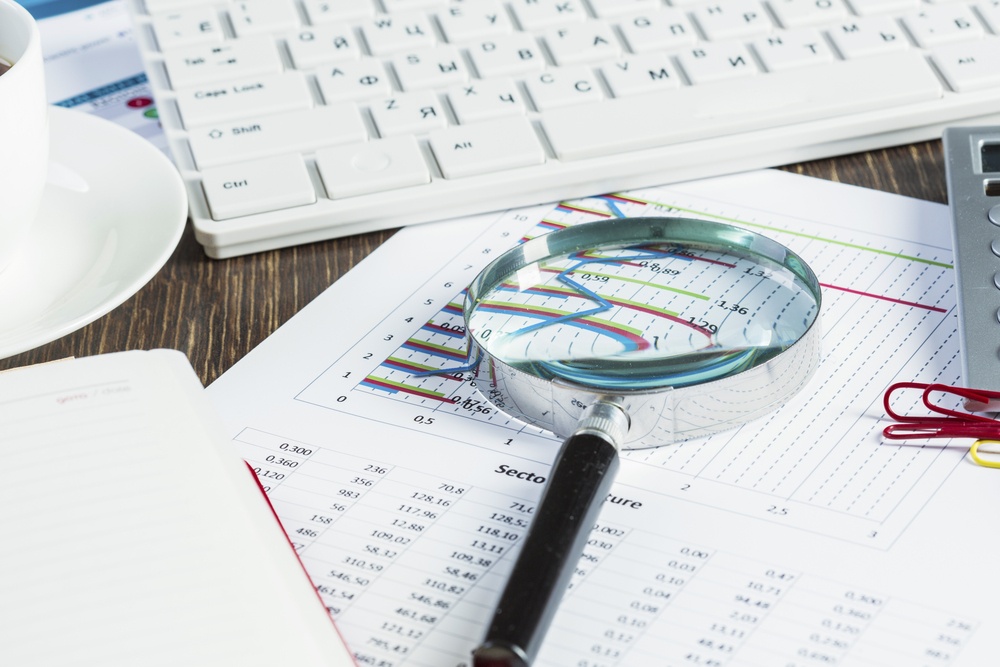 Magnifing glass and documents with analytics data lying on table.jpeg
