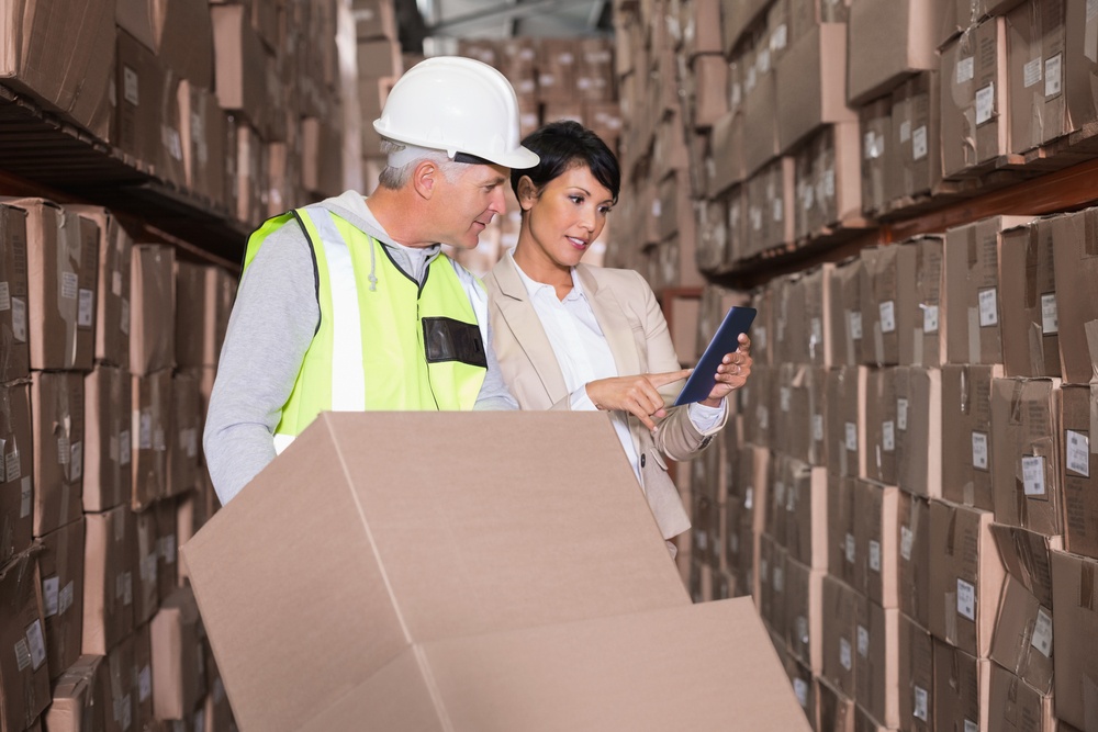 Warehouse worker moving boxes on trolley talking to manager in a large warehouse.jpeg