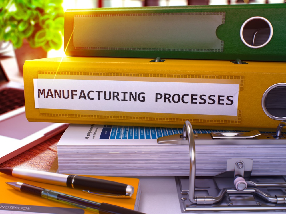 Yellow Ring Binder with Inscription Manufacturing Processes on Background of Working Table with Office Supplies and Laptop. Manufacturing Processes Concept on Blurred Background. 3D Render..jpeg